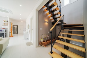 A modern interior with a wooden staircase, a kitchen area, and a living space. - Gangneung Ujin Pool Villa (Gangneung)