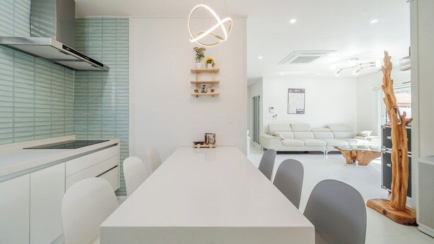 A modern kitchen with a white countertop, a built-in oven, and a hanging light fixture. - Gangneung Ujin Pool Villa (Gangneung)