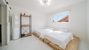 A bedroom with two beds, a wooden floor, a white wardrobe, and a window with a view of a wooden structure outside. - Gangneung Ujin Pool Villa (Gangneung)