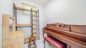Una habitación con un piano, una escalera de madera y un taburete.