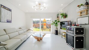 A modern living room with a sofa, a glass coffee table, a TV, and a sound system. - Gangneung Ujin Pool Villa (Gangneung)