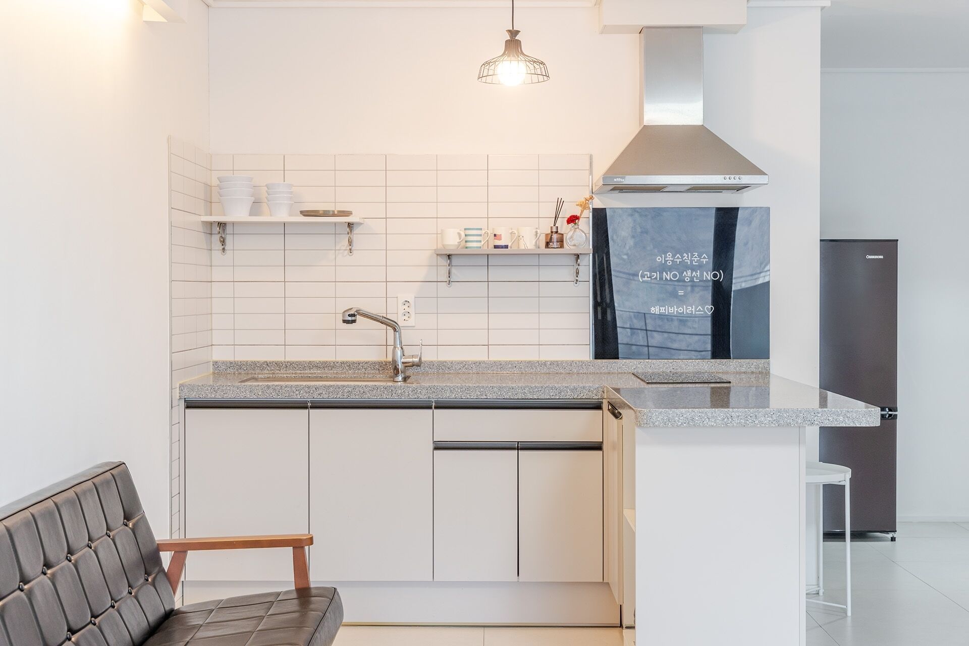 A modern kitchen with a built-in dishwasher, a stainless steel range hood, and a countertop with a sink.