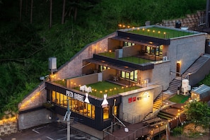 Un immeuble Ă plusieurs Ă©tages dotĂ© dâun jardin sur le toit, dâun espace extĂ©rieur amĂ©nagĂ© et dâun restaurant appelĂ© « Pizza Rabbit ».