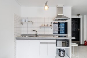 A modern kitchen with white cabinetry, a stainless steel sink, a built-in microwave, and a gas stove.