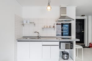 Une cuisine moderne avec des meubles blancs, un évier en acier inoxydable, un four à micro-ondes encastré et une cuisiniÚre à gaz.