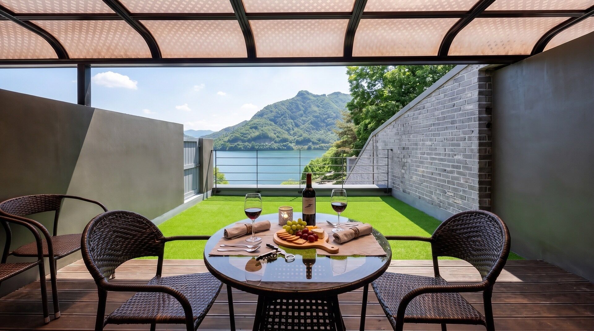A dining area with a table set for two, overlooking a mountain and a body of water.