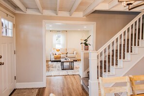 Ein Flur, der in ein Wohnzimmer mit Sofa, Couchtisch und Treppe führt.