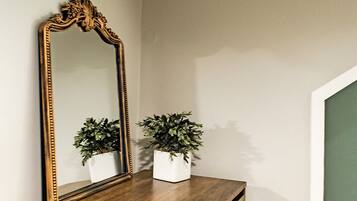 Een houten dressoir met een grote, versierde spiegel en twee potplanten.