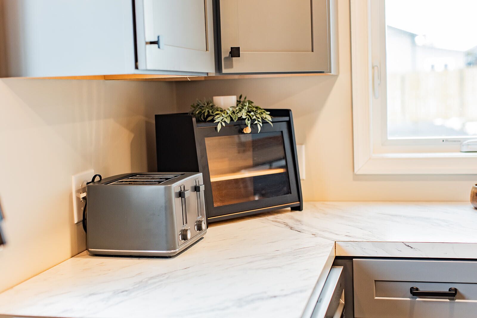 A kitchen with a toaster, a small refrigerator, and a window.