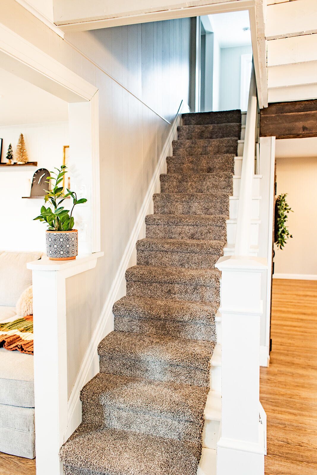Eine Treppe mit Teppichstufen, weißen Geländern und einem Holzboden.