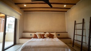 A bedroom with a large bed, a ceiling fan, a ladder, and a view through a glass door. - Oceanfront living with terrace I Long stays welcome (ZIHUATANEJO)