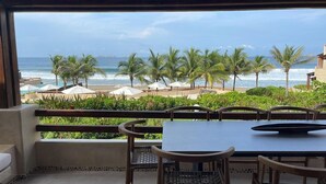 Un balcón con vista a la playa, palmeras y el océano.