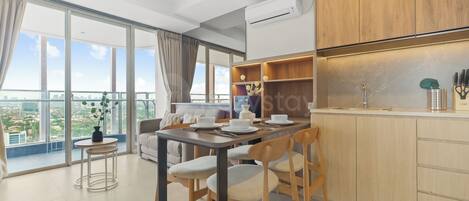Una cocina moderna con armarios de madera, una zona de comedor con mesa y sillas, y un ventanal con vistas a la ciudad.