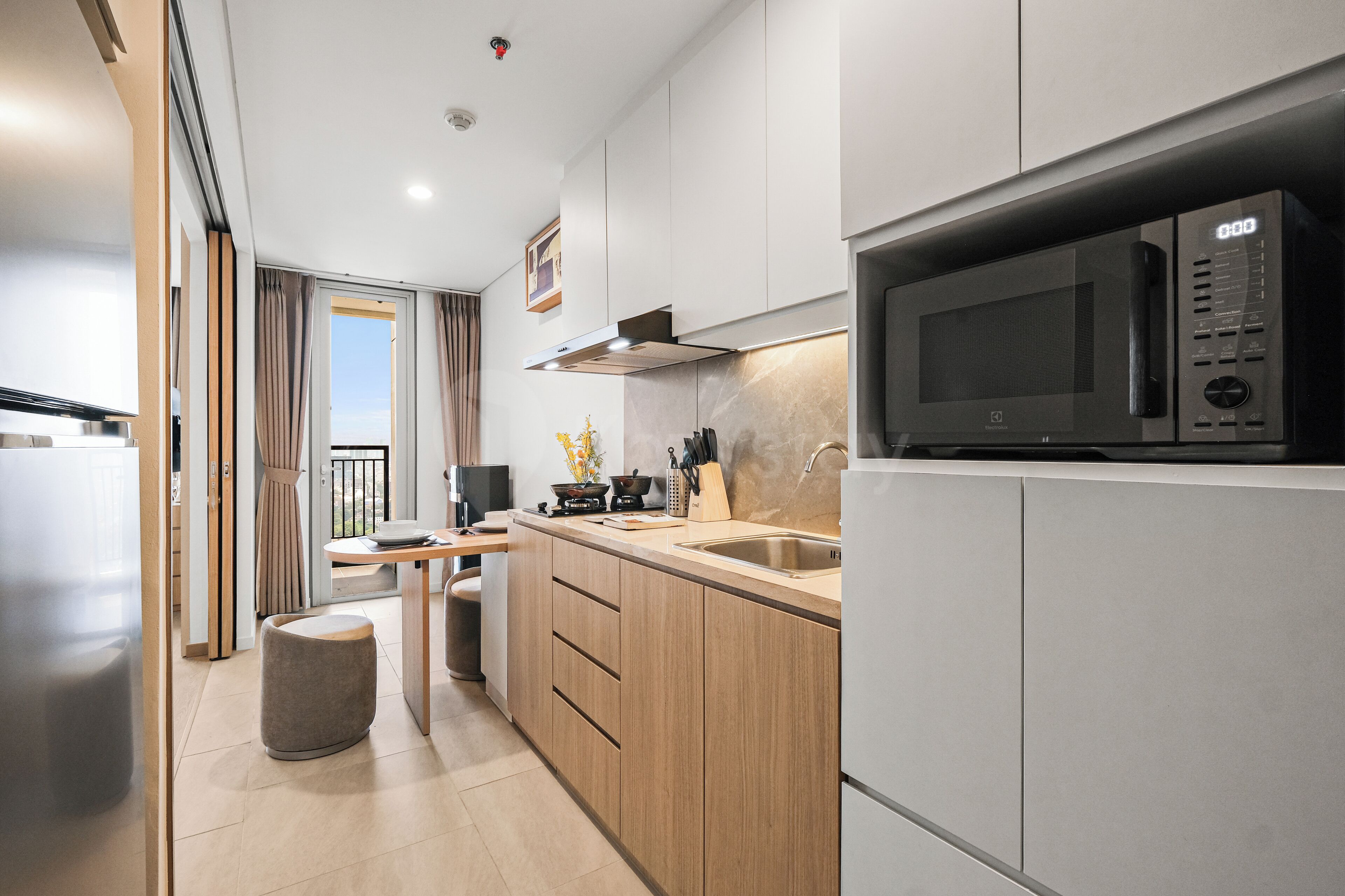 Una cucina moderna con forno a microonde integrato, elettrodomestici in acciaio inossidabile, mobili in legno e un'ampia finestra.