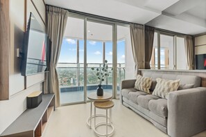 A modern living room with a sofa, a small table, and a TV mounted on the wall. - Premium Apartment by Kozystay - Antasari Place (Kota Jakarta Selatan)