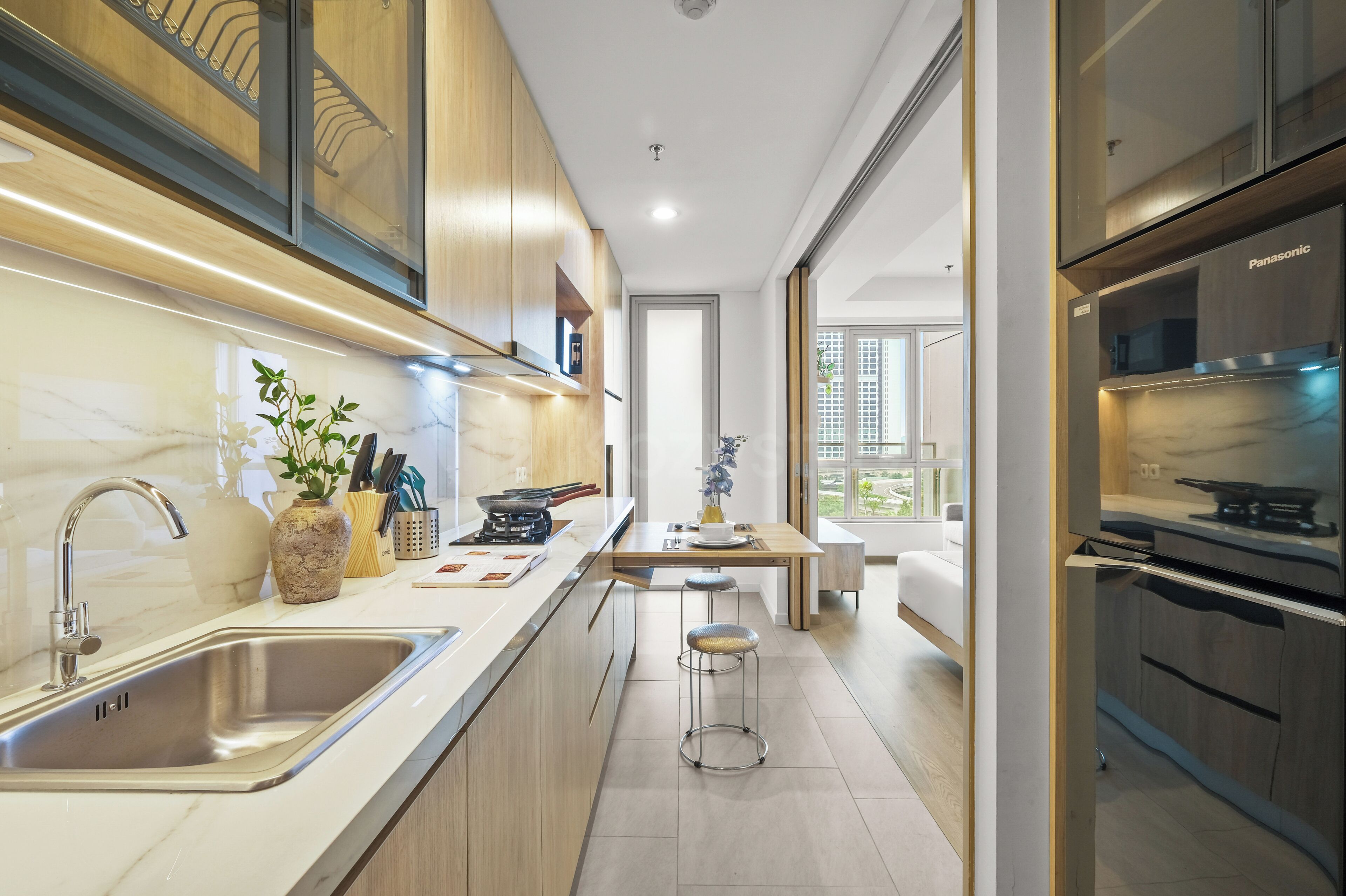 A modern kitchen with a built-in stove, a sink, and a dining area with a table and chairs.