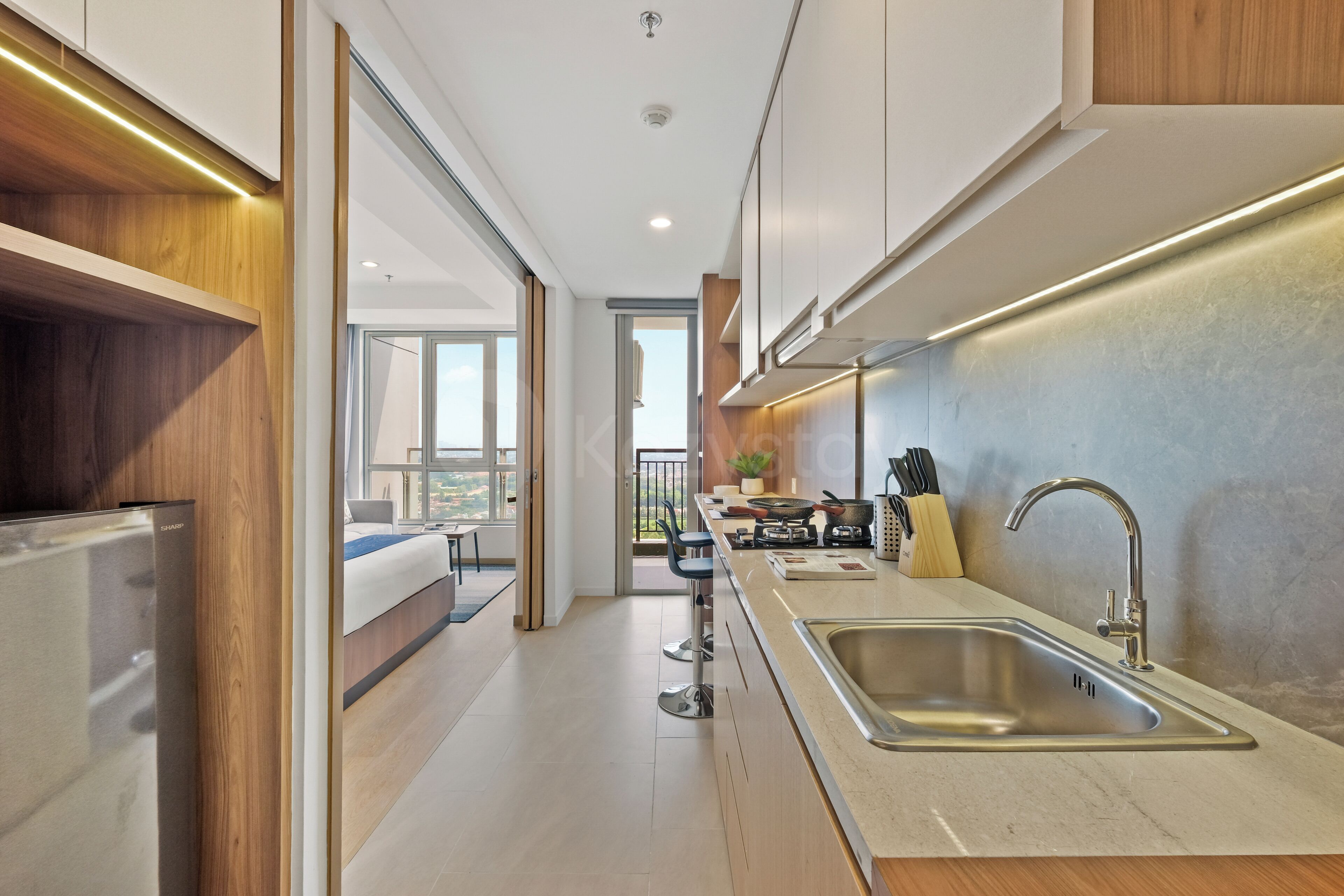 A modern kitchen with a stainless steel sink, wooden cabinets, and a view to the outside.
