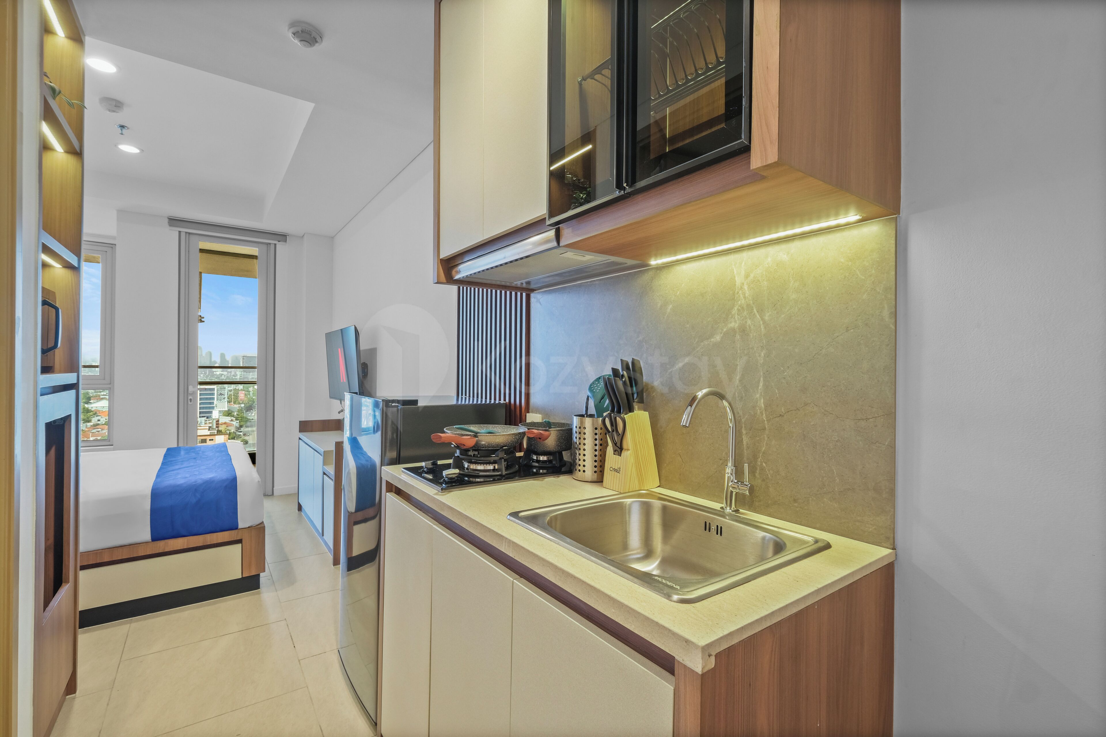 A compact kitchen with a sink, stove, and cabinets, a bed with a view, and a small dining area.