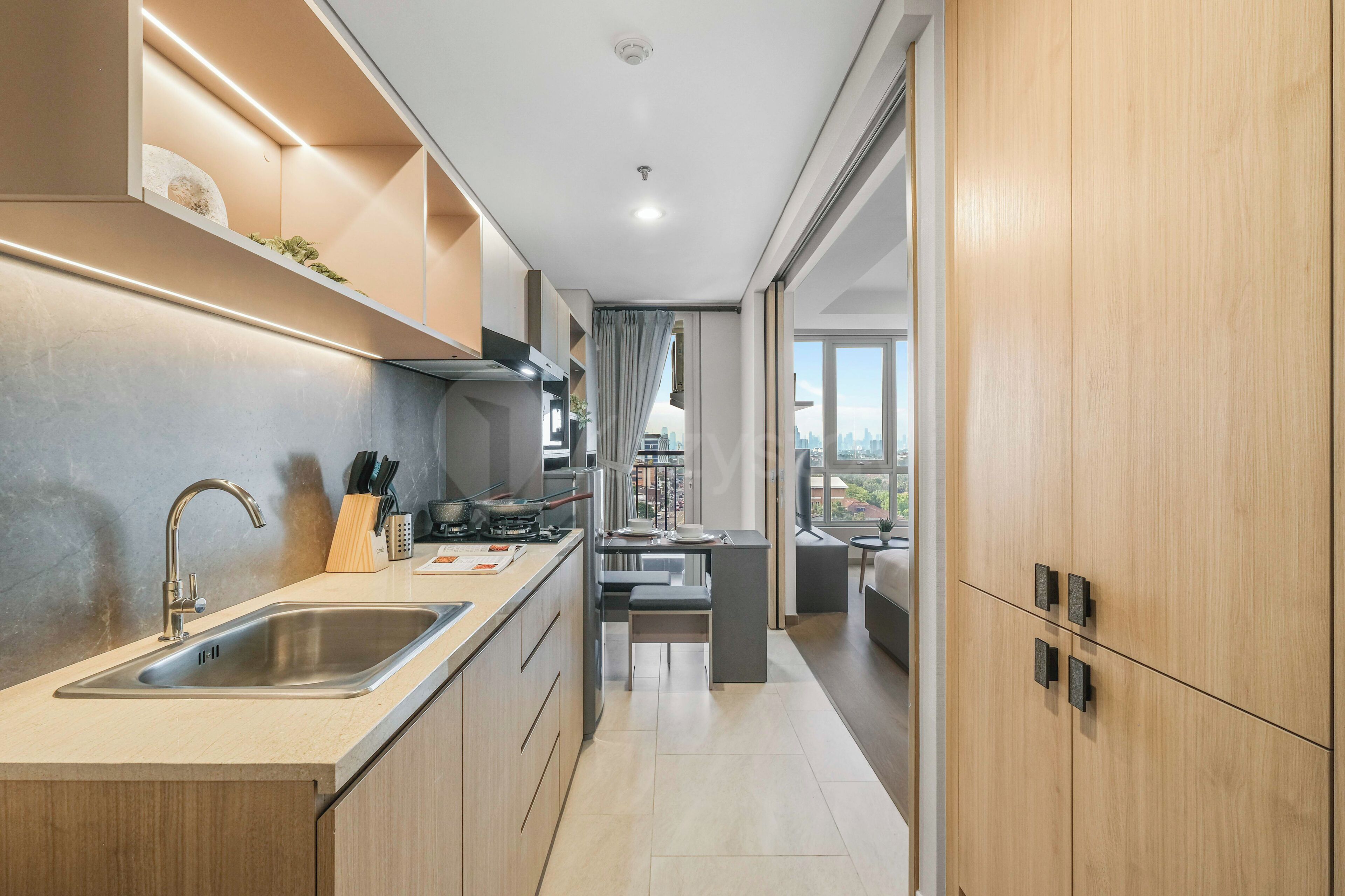 A modern kitchen with a built-in stove, a sink, and a window overlooking a cityscape.
