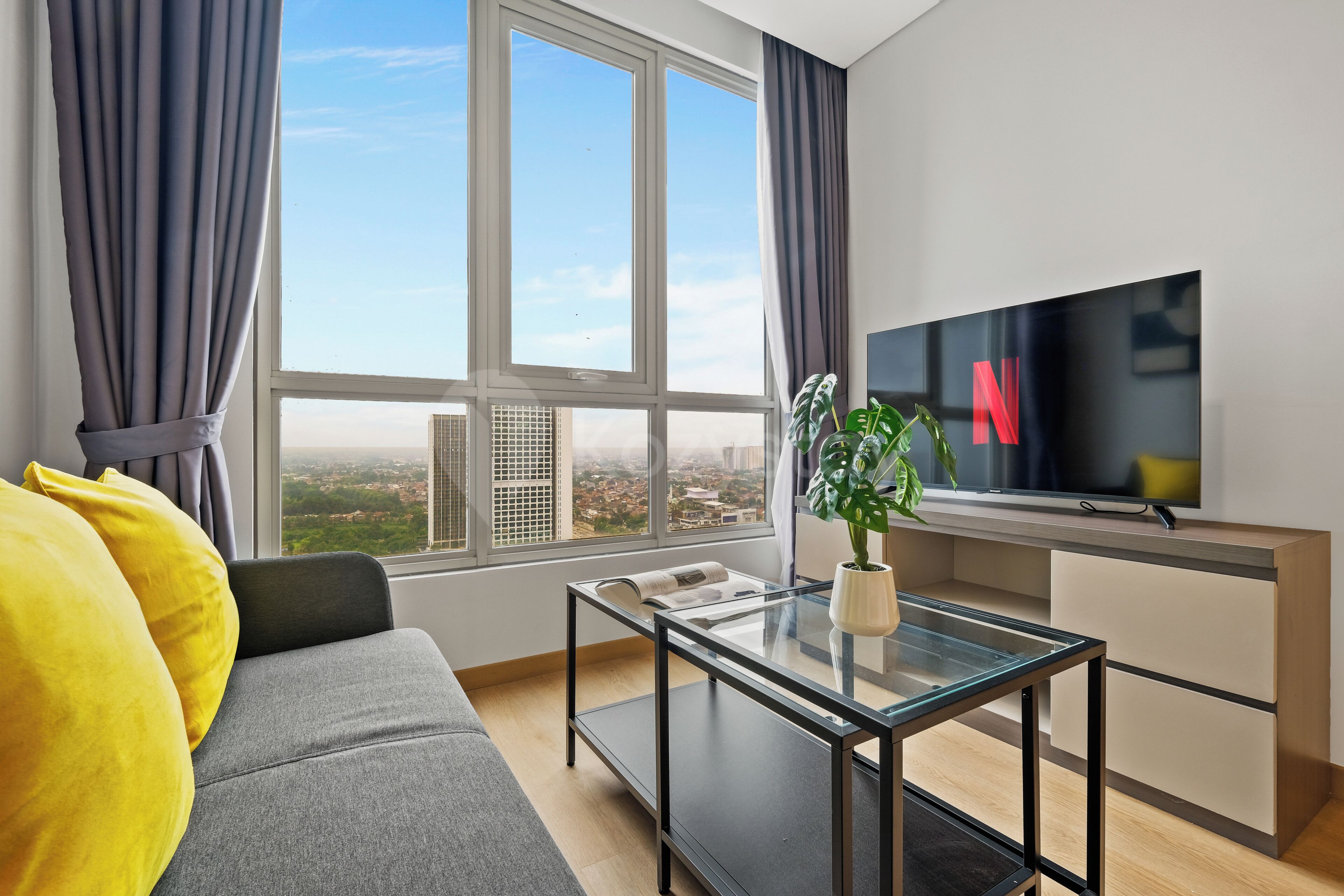 A modern living room with a sofa, a glass coffee table, and a television.