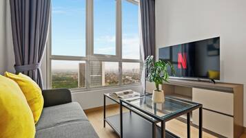 A modern living room with a sofa, a glass coffee table, and a television.