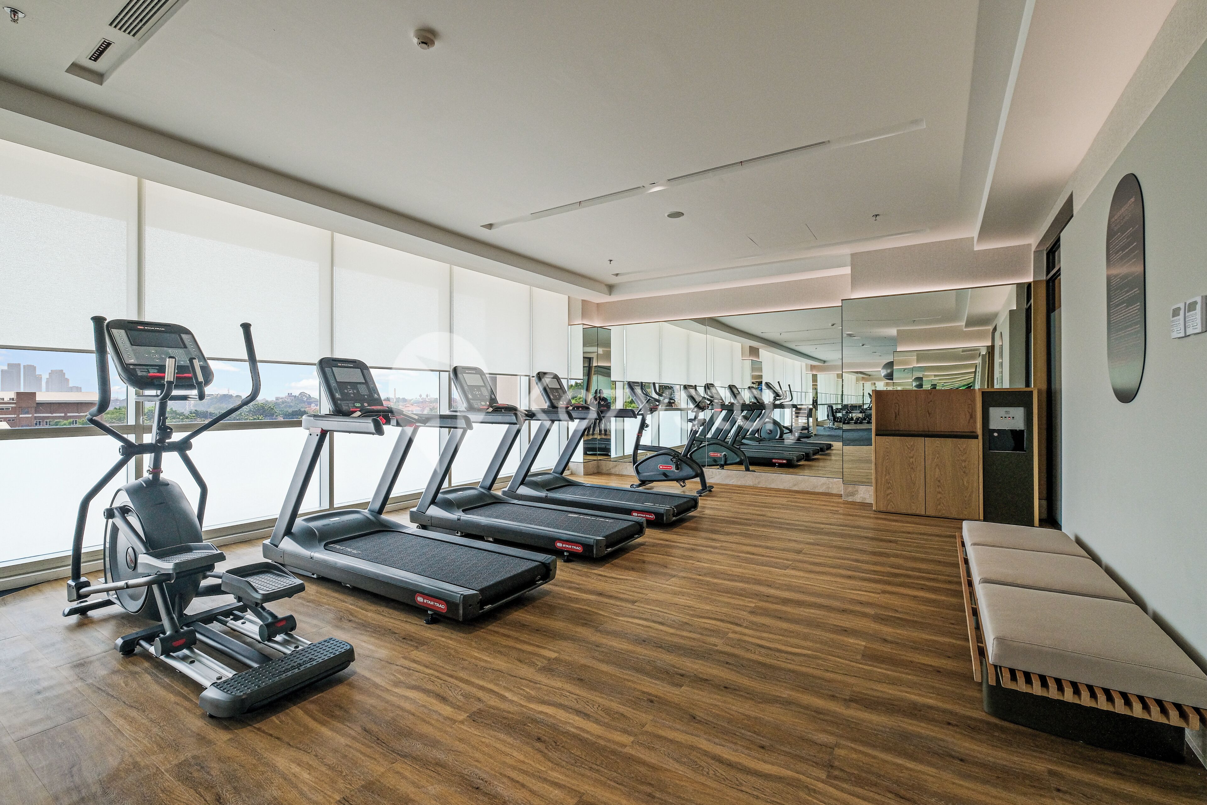 A modern gym with multiple treadmills, a rowing machine, and a bench.