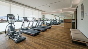 A modern gym with multiple treadmills, a rowing machine, and a bench. - Premium Apartment by Kozystay - Antasari Place (Kota Jakarta Selatan)