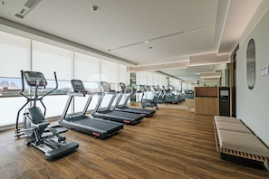 A modern gym with multiple treadmills, a rowing machine, and a bench. - Premium Apartment by Kozystay - Antasari Place (Kota Jakarta Selatan)