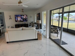 A modern living room with a sofa, television, and a large window. - 3-bedroom house in pleasant Port Charlotte with cool AC (Port Charlotte)
