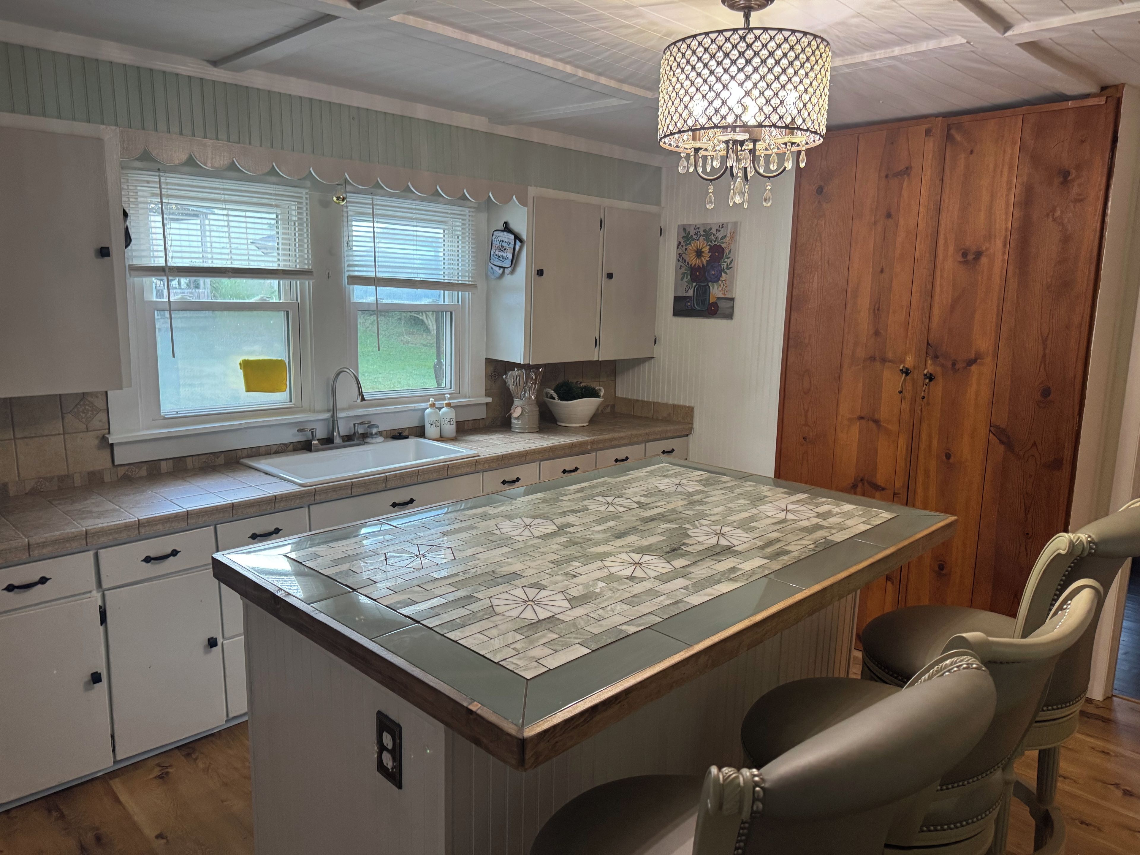 A kitchen with a central island, wooden cabinets, a sink, and a chandelier.