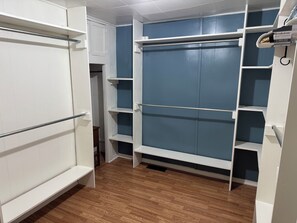 Ein begehbarer Kleiderschrank mit weißen Regaleinheiten und einer blauen Schiebetür.