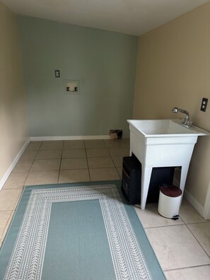 Un baño pequeño con un lavamanos blanco, un espejo y una alfombra estampada en el suelo.