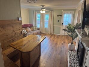 A cozy living room with a wooden bench, a sofa, and a television. - Charming 3-bedroom bungalow in enjoyable West Liberty (West Liberty)