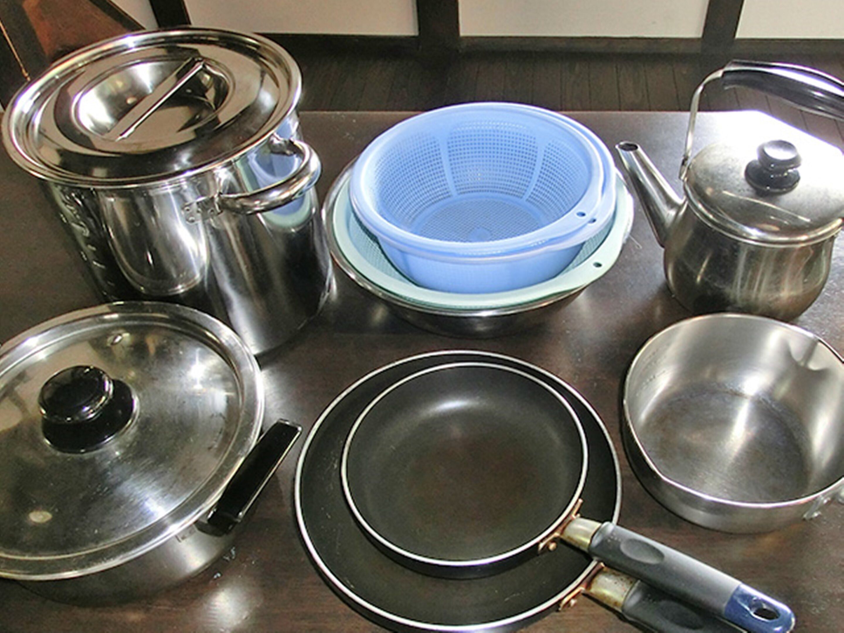 Une cuisine équipée d’ustensiles de cuisine en acier inoxydable, notamment des casseroles, des poêles et une poêle à frire.