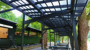 Un'area picnic riparata con panche, un piccolo edificio con una porta e delle scale che vi conducono.