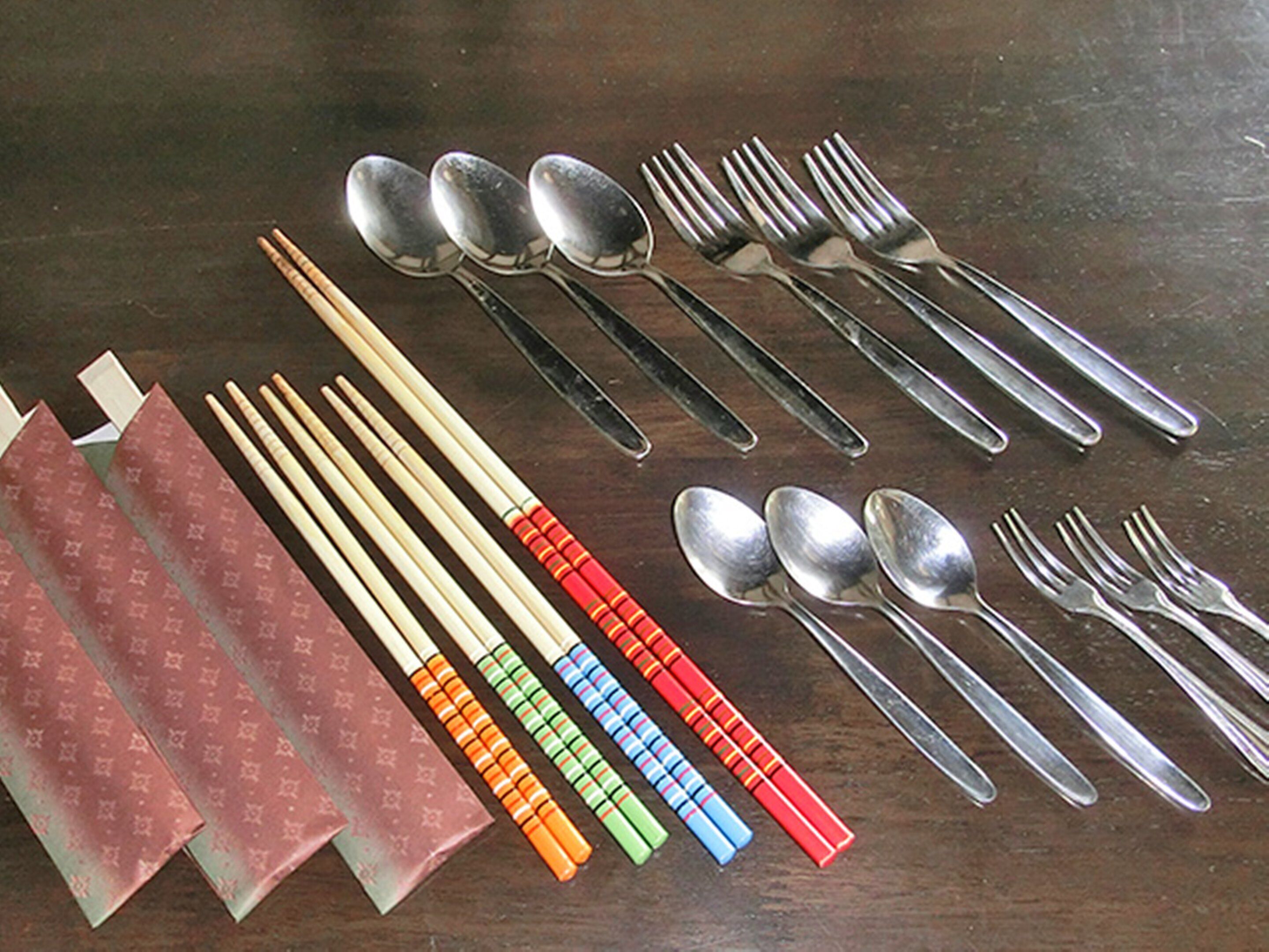 A table with various utensils including chopsticks, spoons, and forks.