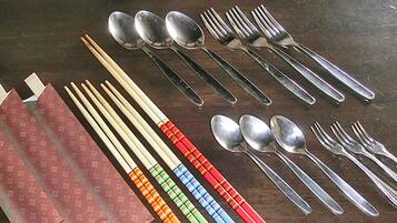 A table with various utensils including chopsticks, spoons, and forks.