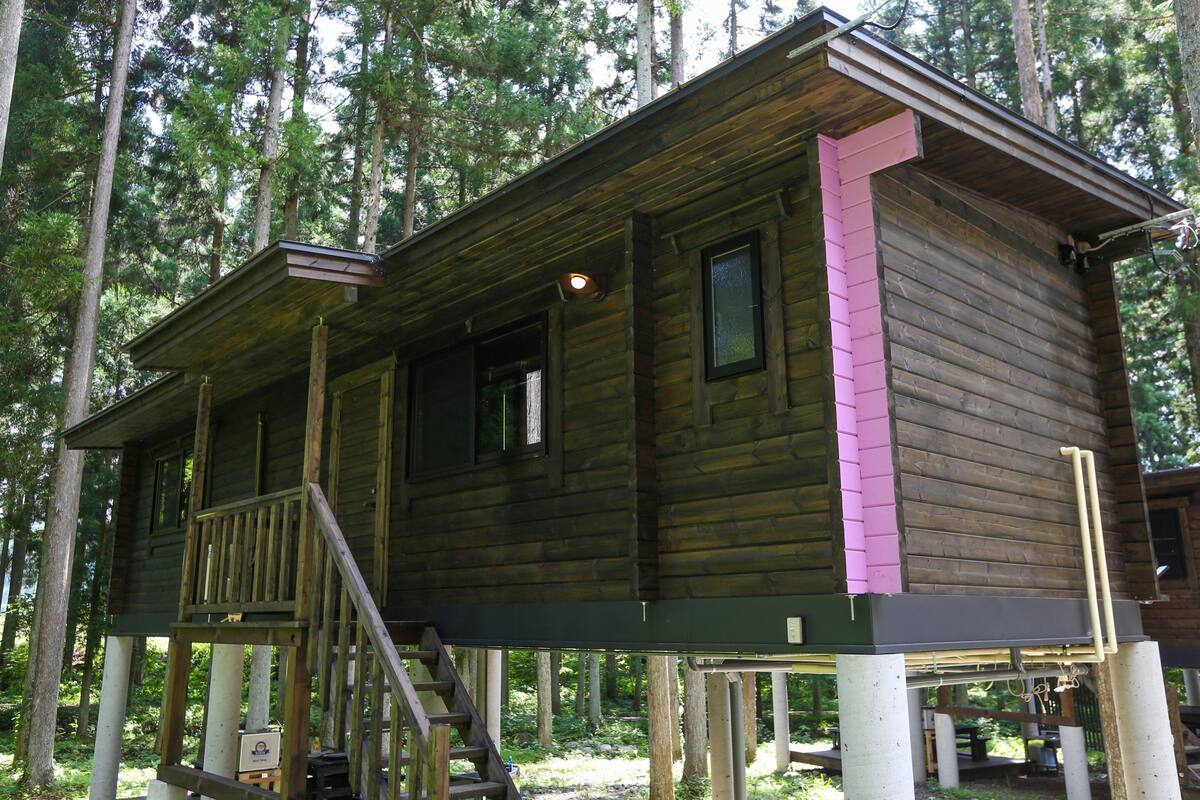 A wooden cabin with a porch, a staircase, and a small deck area.