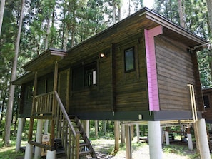 A wooden cabin with a porch, a staircase, and a small deck area.