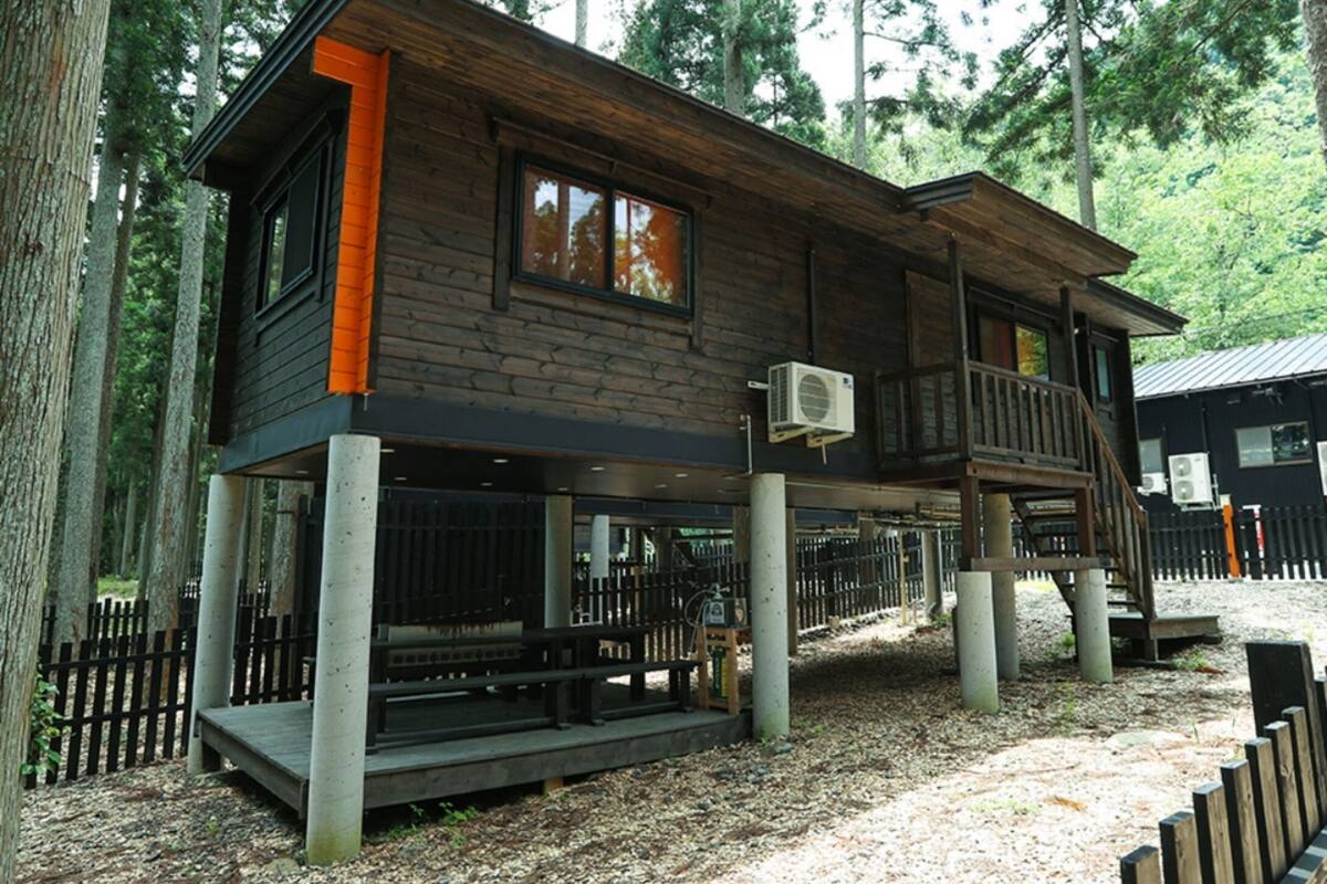 A cabin with a deck, large windows, and an air conditioning unit.