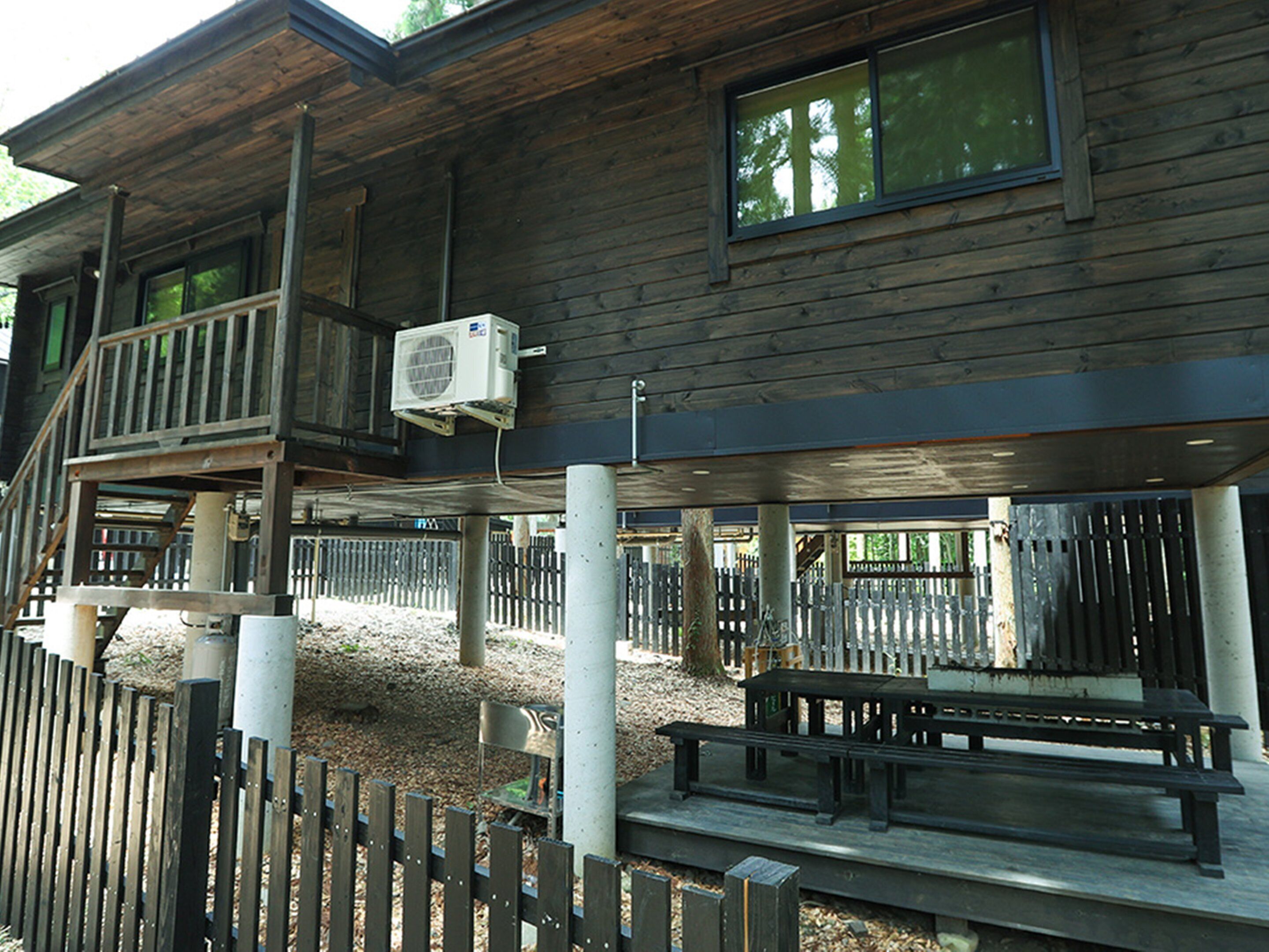 Una cabaña de madera con balcón, mobiliario exterior y un área cercada.