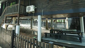 Una baita di legno con un balcone, posti a sedere all'aperto e una recinzione.