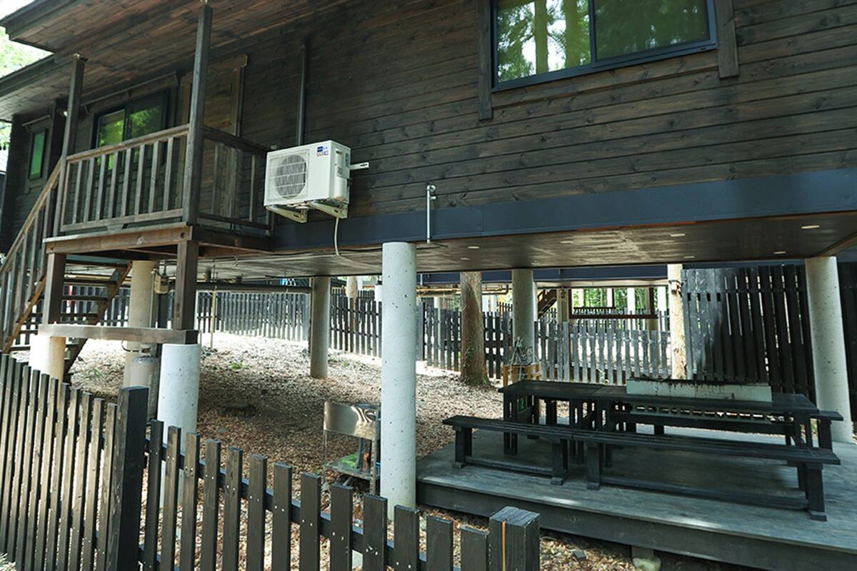 A wooden cabin with a balcony, outdoor seating, and a fence.
