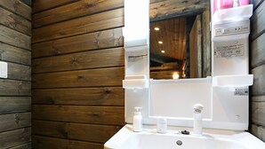 Un bagno con pareti in legno, un lavandino bianco e uno specchio.