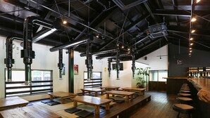 A restaurant with wooden tables and stools, a bar area, and visible ductwork on the ceiling. - Nagomiya Seseragi (Gujo)