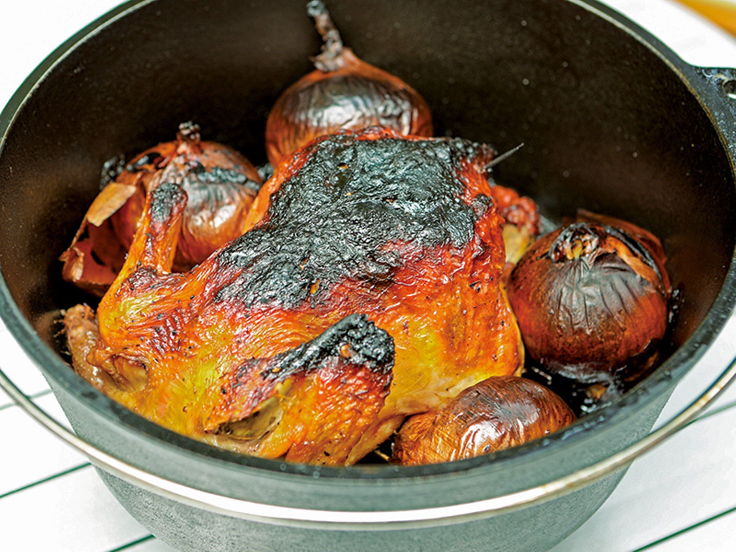 Una olla con pollo asado y cebollas.