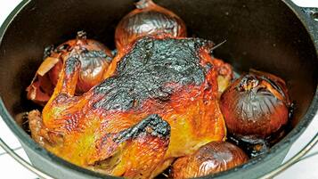Una olla con pollo asado y cebollas.
