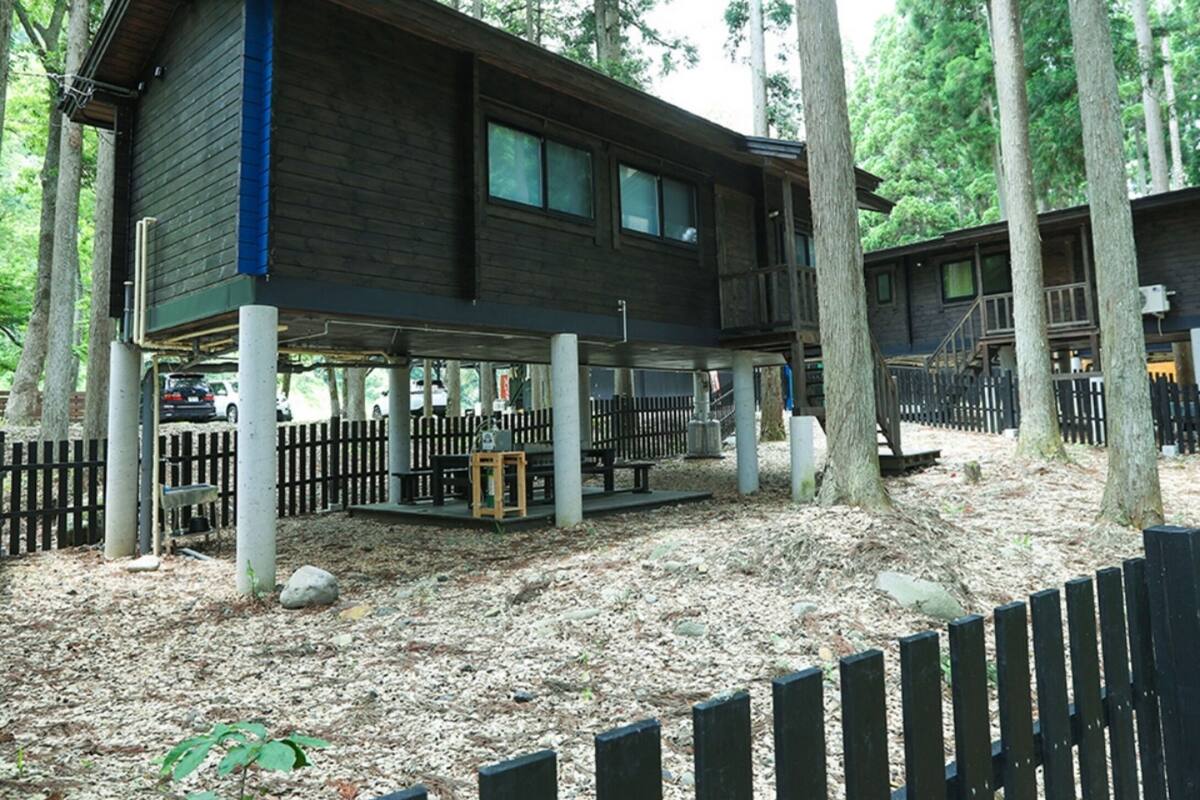 A cabin with a wooden exterior, a covered porch, and a fenced outdoor area.