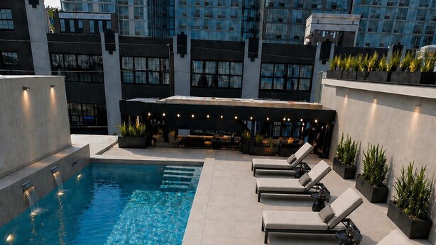 A rooftop pool with clear blue water, surrounded by lounge chairs and potted plants. -  Hoboken Grand House- 3 Bedroom 2.5 Bathroom with a private rooftop (Hoboken)