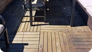 A rooftop deck with a wooden table and chairs, a red umbrella, and a view of the cityscape. -  Hoboken Grand House- 3 Bedroom 2.5 Bathroom with a private rooftop (Hoboken)